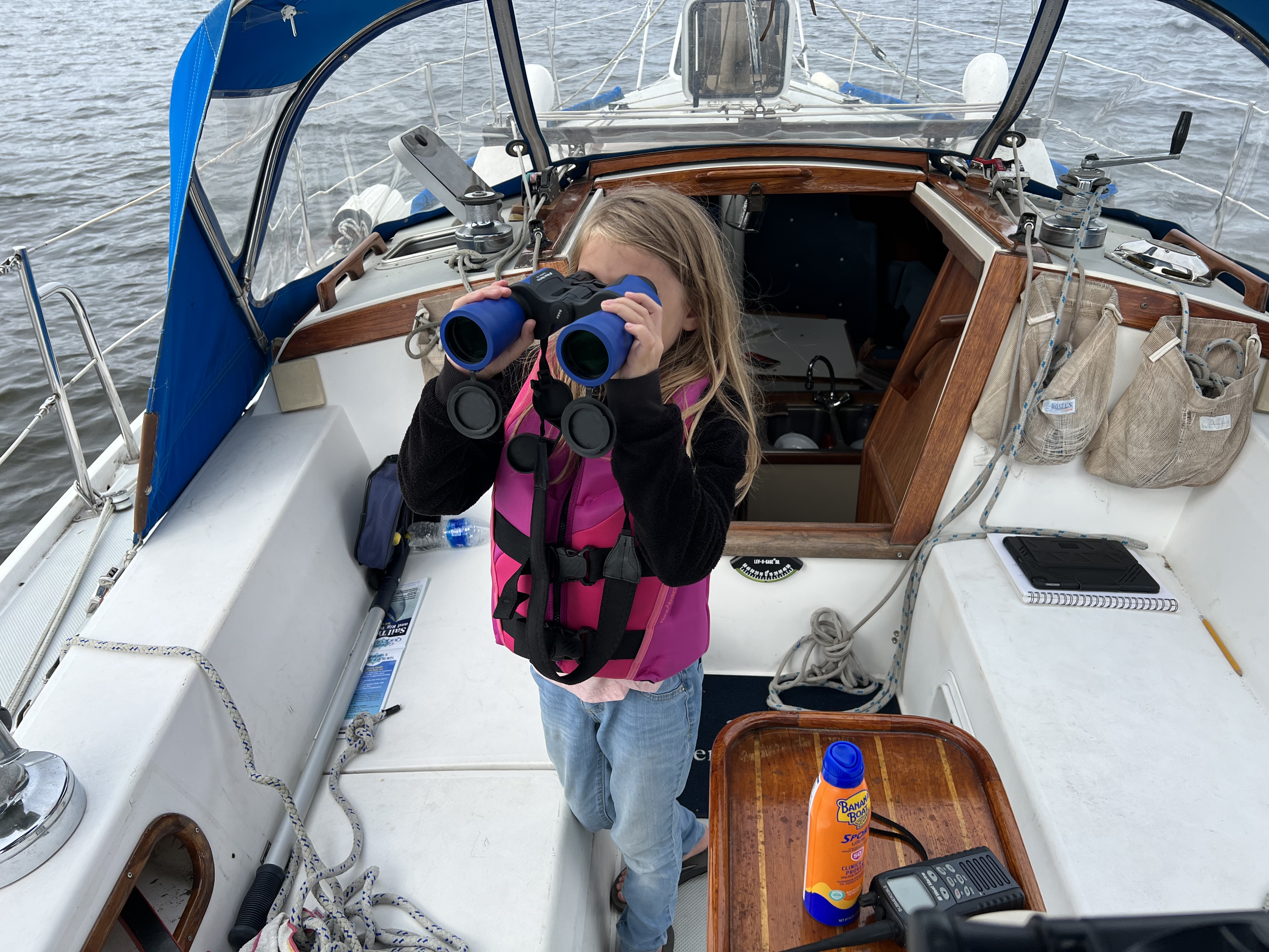 Hanna with binoculars in the cockpit of Seventh Heaven